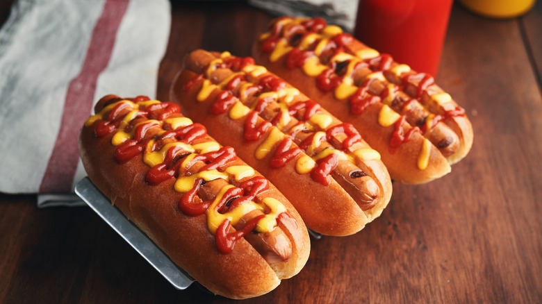 three hot dogs drizzled with mustard and ketchup