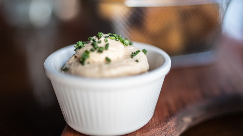 a small cup of creamy aioli topped with green onions