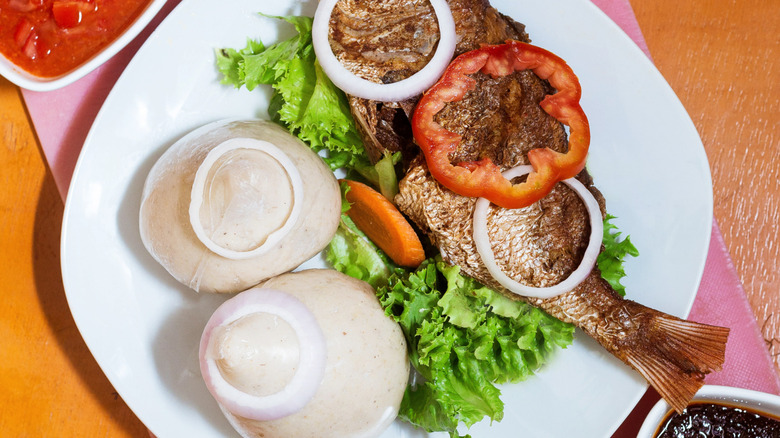 Grilled tilapia with banku and sliced vegetables