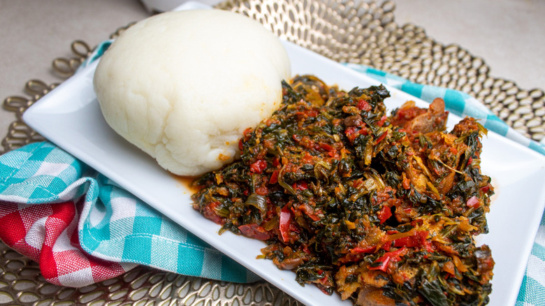 Fufu alongside vegetable stew on white plate