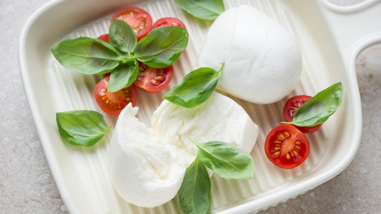 torn mozzarella di bufala with cherry tomatoes and basil leaves