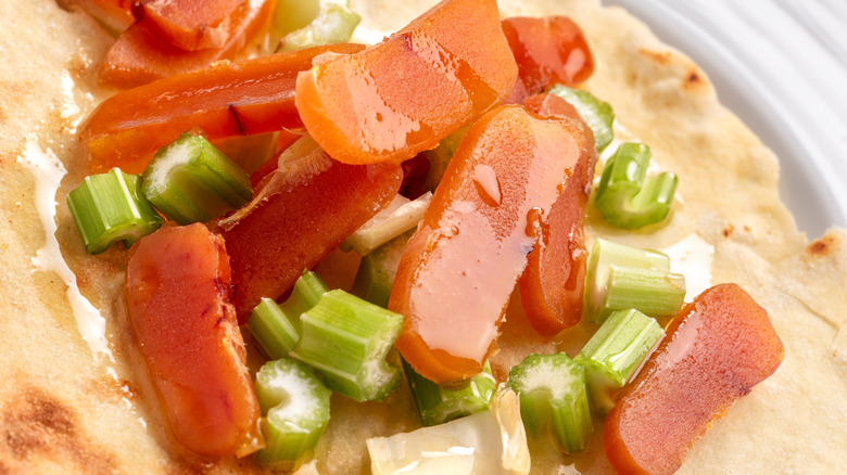 Slices of orange bottarga with celery on flatbread