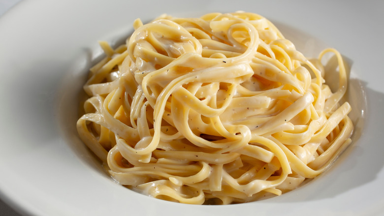white plate holding ribbons of pasta dressed with creamy sauce