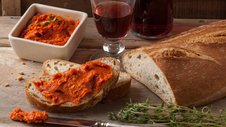 Bright orange spreadable salami paste 'nduja on bread with glass of red wine