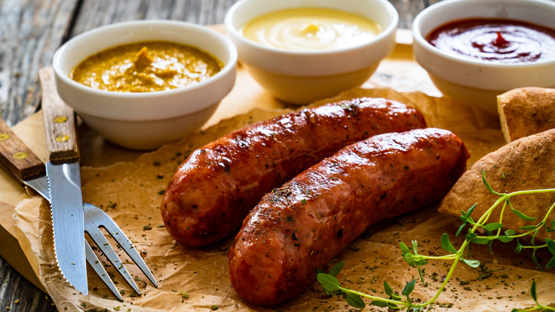 Sausage on parchment with dipping sauces and cutlery