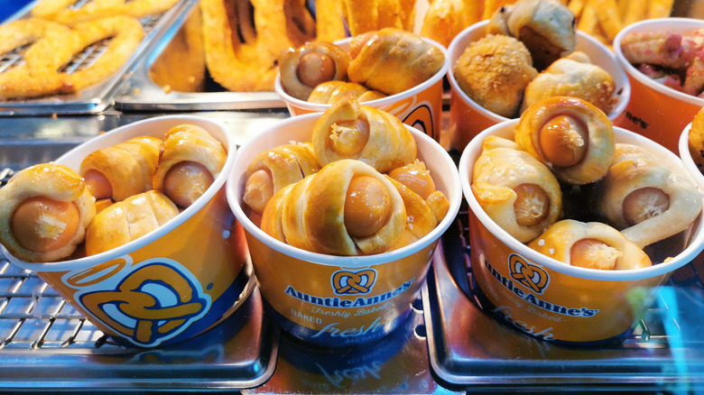Cups of Auntie Anne's pretzel dogs in front of pretzels