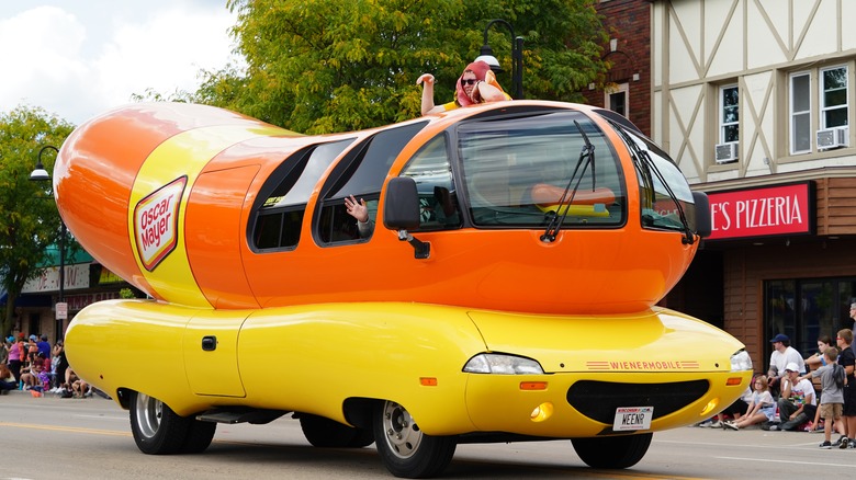 Oscar Mayer Wienermobile on parade with waving rider dressed like a hot dog