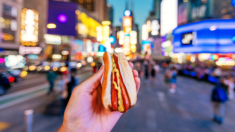 Hand held hot dog with mustard in Times Square