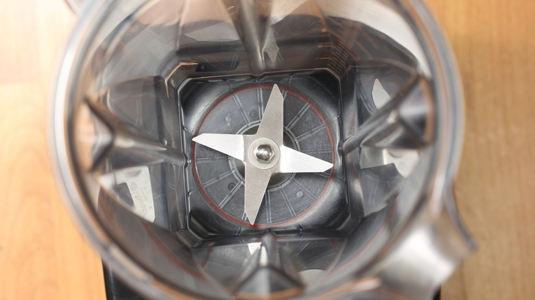 an empty blender jar with a four pronged blade at the bottom.