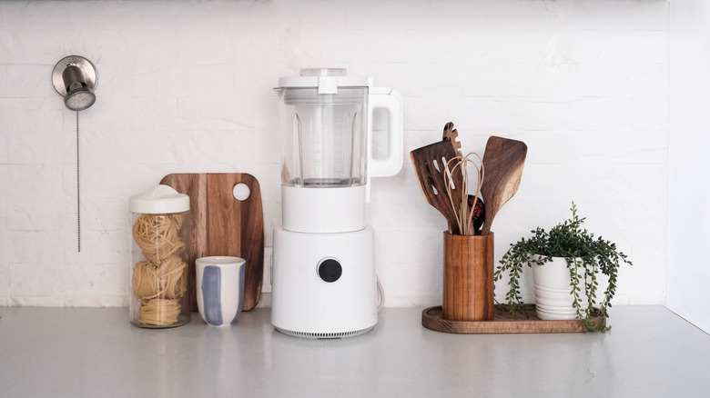 a white blender set on a countertop between other cooking accessories.