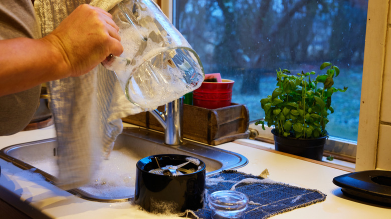 blender being hand washed at a kitchen sink with a towel.