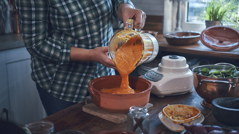 a blender full of orange puree being poured into a dish.