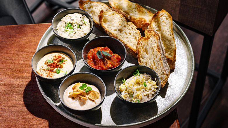 Metal ramekins filled with dip on a plate with bread.