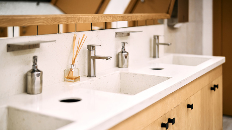 Restroom sink area with air freshener and soap bottles.