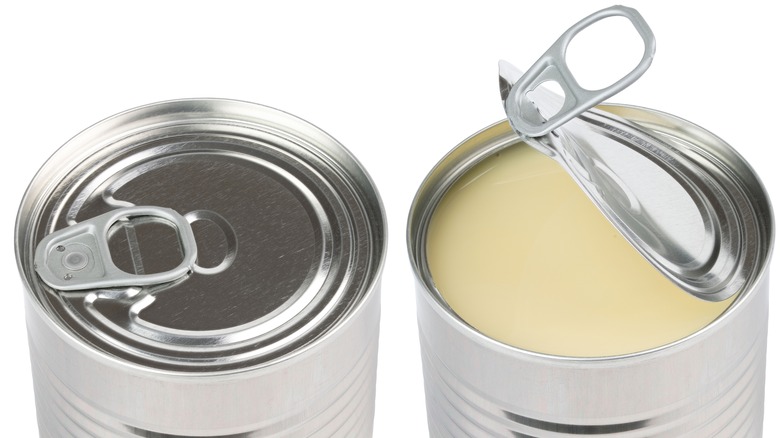 Cans of condensed milk with the top of one pulled open