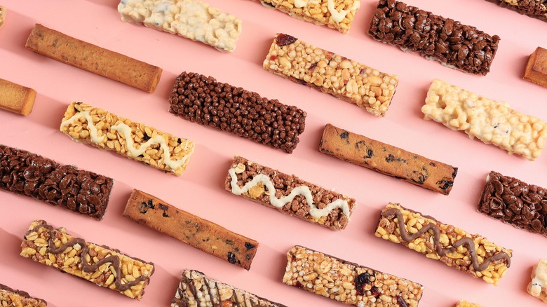 An array of energy bar varieties arranged neatly before a pink background