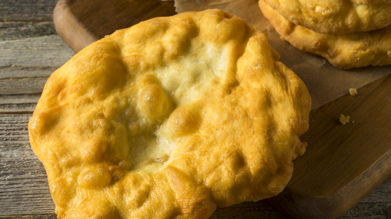 Golden fry bread resting on wooden board and table