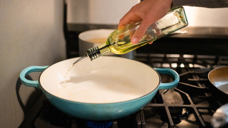 Man's hand pouring oil into a pan