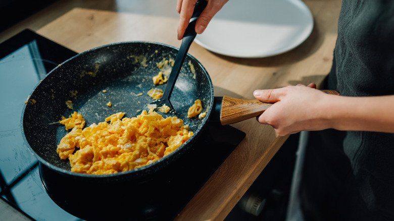 Person cooks scrambled eggs