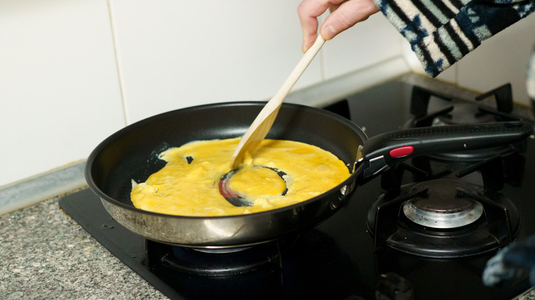Person making scrambled eggs in a frying pan