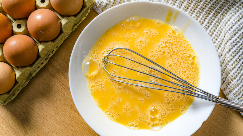 Scrambled raw eggs in a white bowl