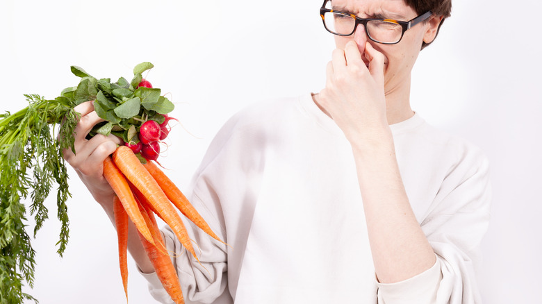 Person recoiling from smelly produce in hand