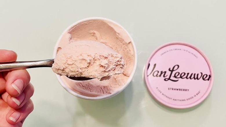 Hand scooping spoonful of Van Leeuwen Strawberry Ice Cream from pint