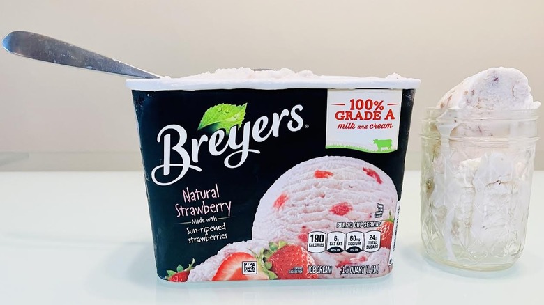 Glass full of Breyers Natural Strawberry Ice Cream with carton on side