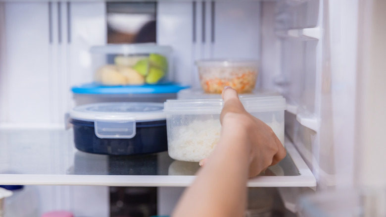 hand place plastic container fridge