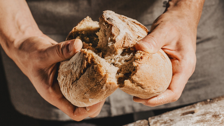 person tearing loaf of bread