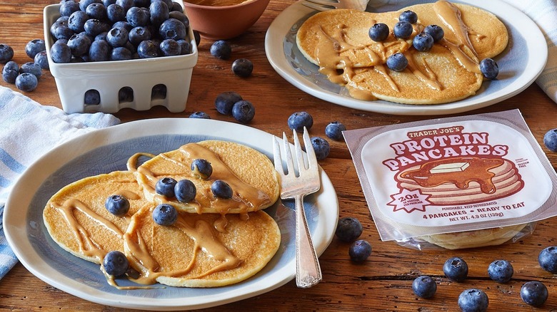 Trader Joe's protein pancakes on plates with peanut butter drizzle and blueberries