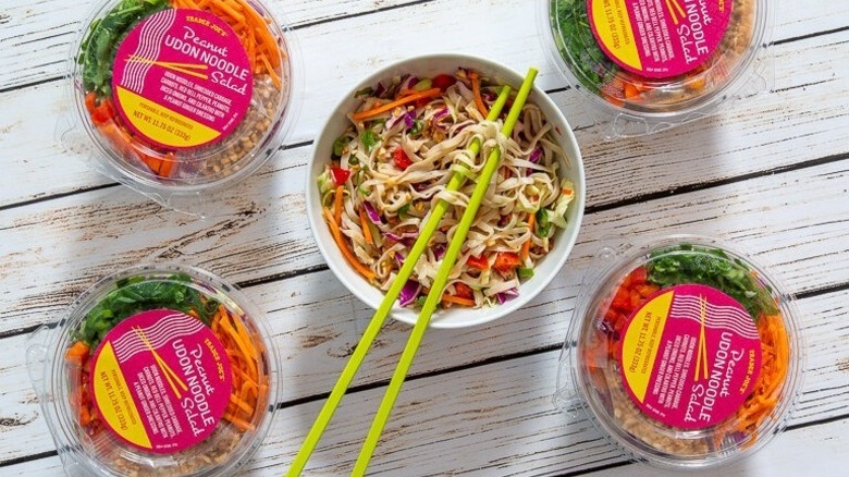 Four packages of Trader Joe's Peanut Udon Noodle Salad surround a bowl of the salad