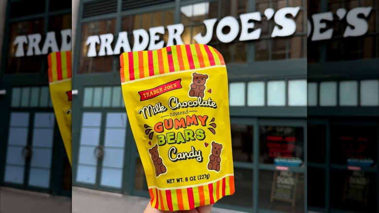 A bag of Trader Joe's Milk Chocolate Covered Gummy Bears held up in front of a TJ's