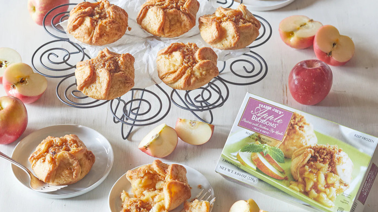 A box of Trader Joe's Apple Blossoms sits next to Apple Blossoms displayed on plates and a dessert rack
