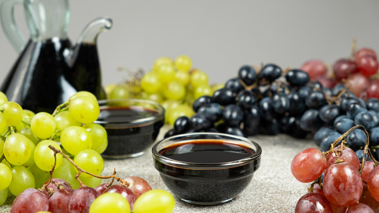 a bowl of dark aged vinegar surrounded by grapes