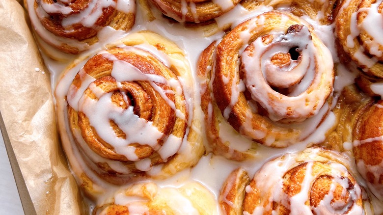 a pan of cinnamon rolls soaking in cream