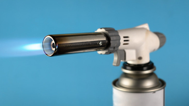 a kitchen torch burner throws a blue flame