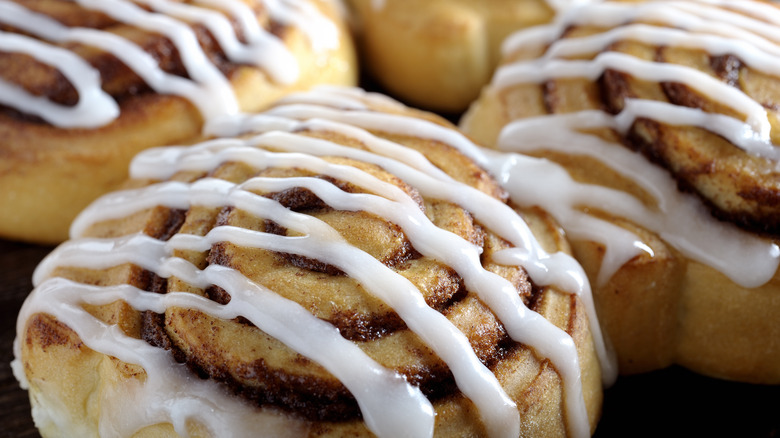 a tray of store bought cinnamon buns drizzled in icing