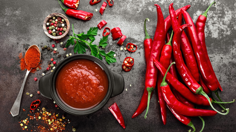 Red chili peppers with seasonings and a dish of spicy sauce