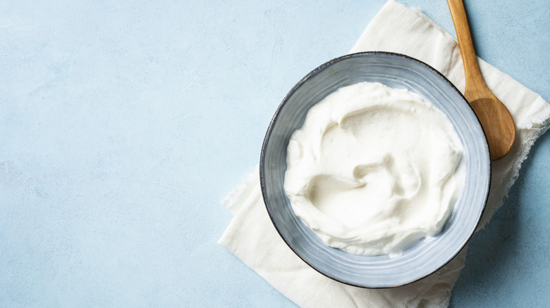 Blue ceramic bowl of Greek yogurt with a wooden spoon