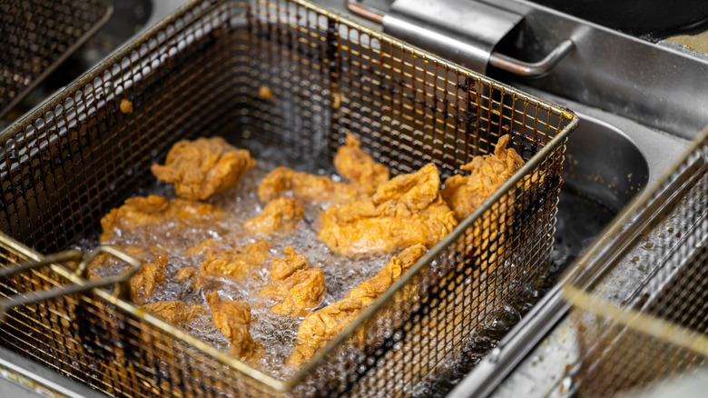Chicken tenders submerged in deep fryer