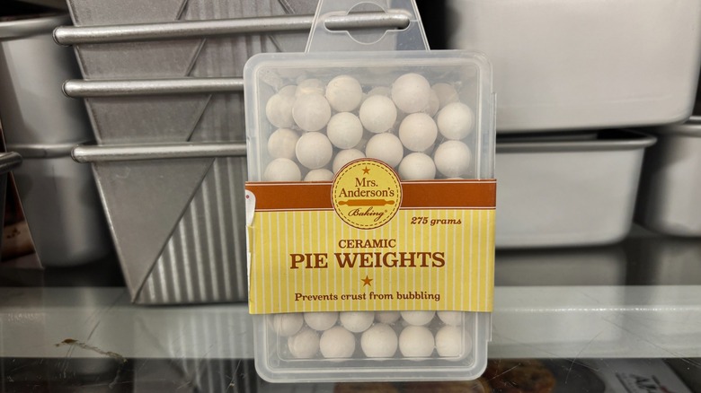 A plastic container of ceramic pie weights sits on a store shelf.