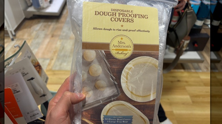 A person is holding a bag of disposable dough proofing covers in a HomeGoods store.