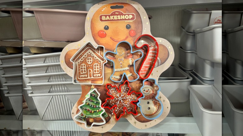 A package of holiday cookie cutters sits in front of baking pans on a store shelf.