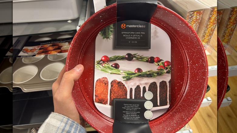 A person holds a red springform cake pan in a store.