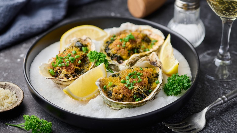 Oysters Rockefeller on a plate with lemon wedges
