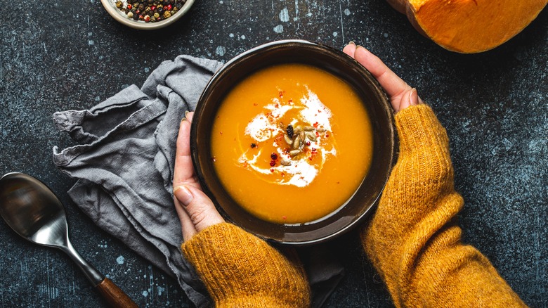 Hands holding soup in bowl