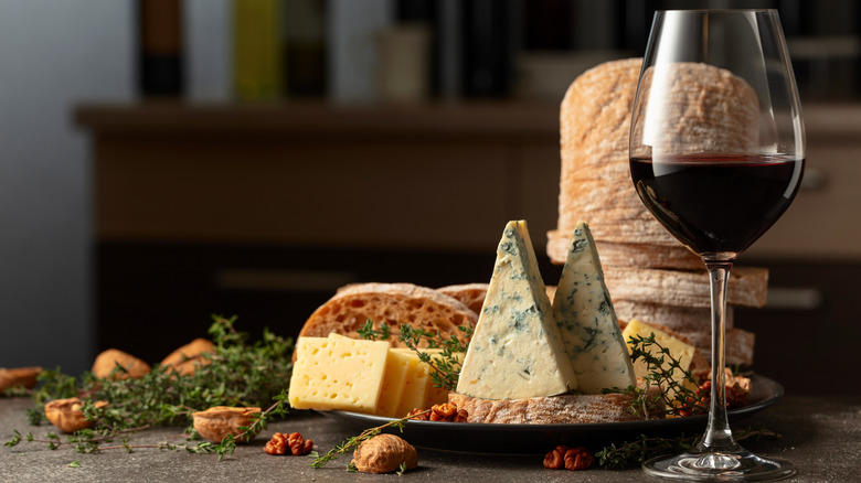 wooden board filled with worldly cheeses and red wine glass