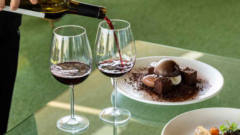 red wine being poured into a glass next to chocolate