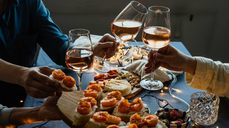 glasses of white/rosé wine, food, and people at a table